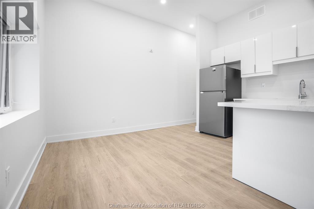 A kitchen area with a refrigerator, cabinets, and a countertop.