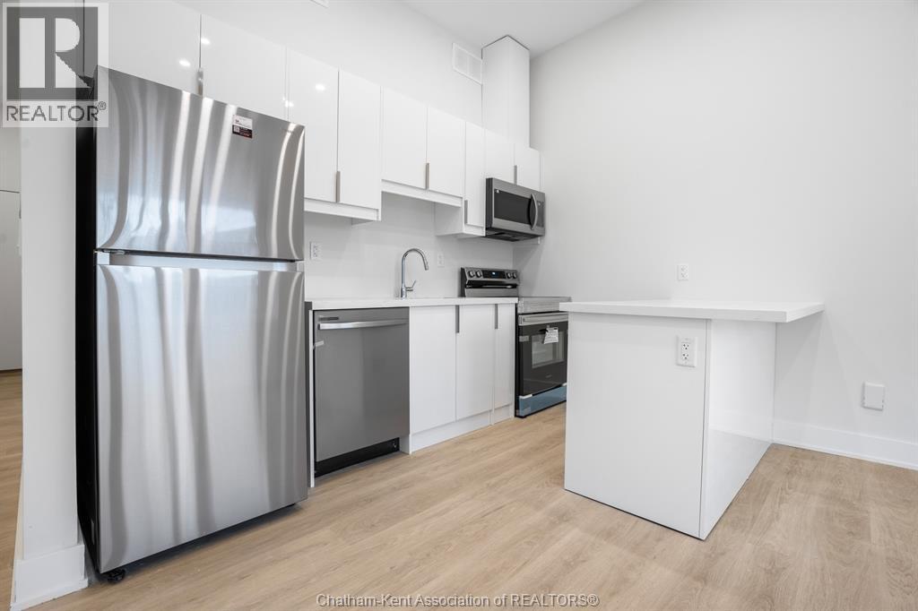 A kitchen with a refrigerator, microwave, oven, and sink.