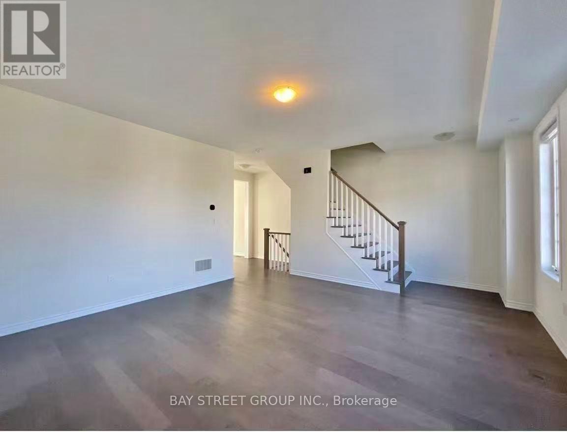 A spacious room with a staircase and wooden flooring.