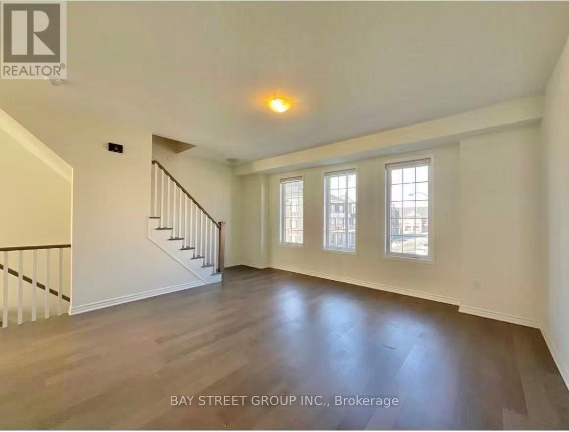 A spacious room with a staircase and three windows.