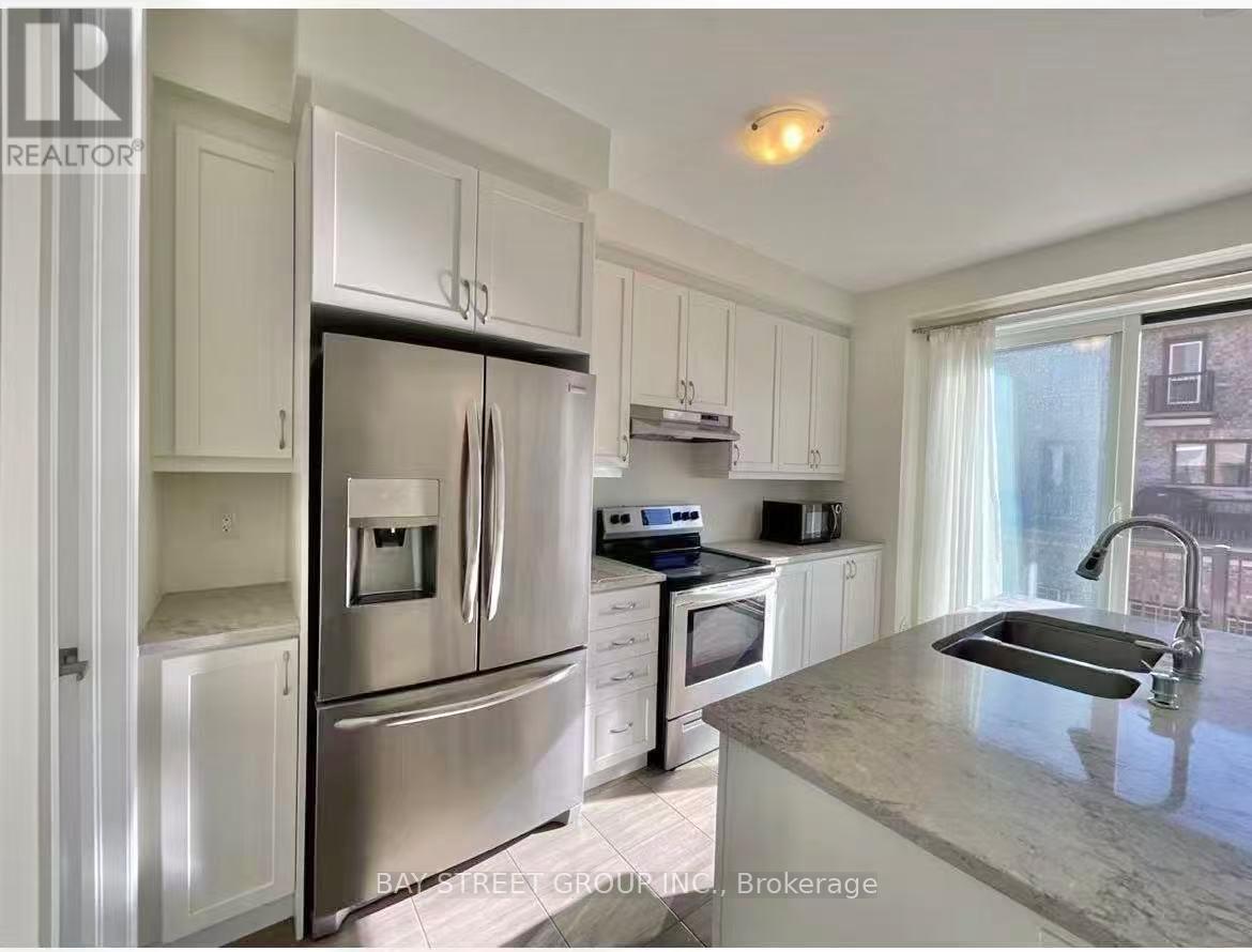 A kitchen with a refrigerator, microwave, oven, sink and cabinets.