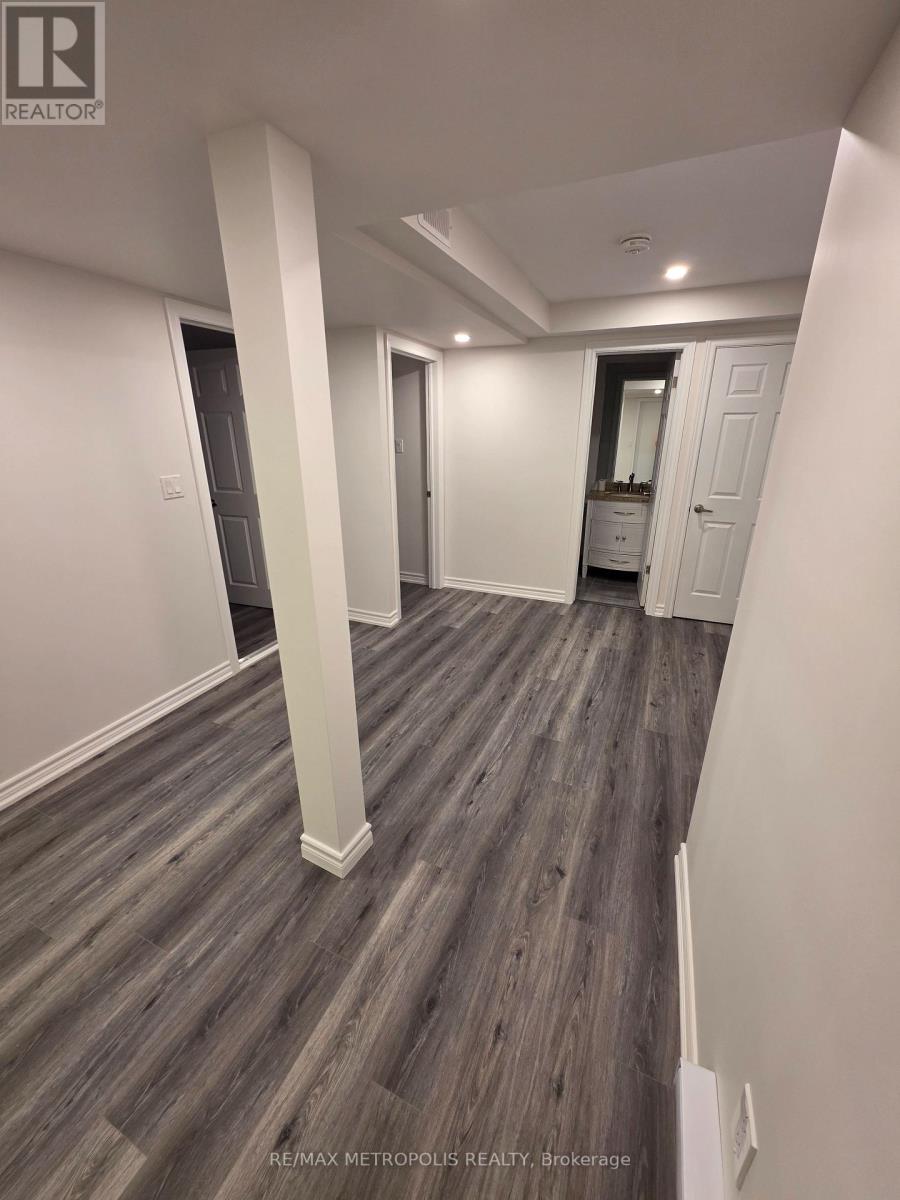 A spacious room with wood flooring and white walls.