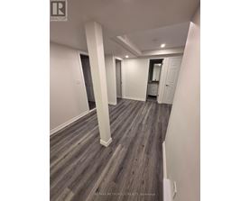 A spacious room with wood flooring and white walls.