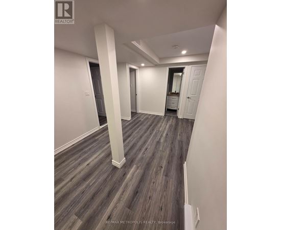 A spacious room with wood flooring and white walls.