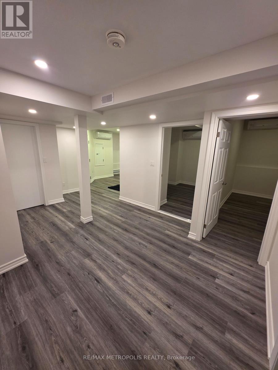 A spacious room with wooden flooring and white walls.