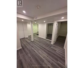A spacious room with wooden flooring and white walls.