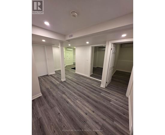 A spacious room with wooden flooring and white walls.