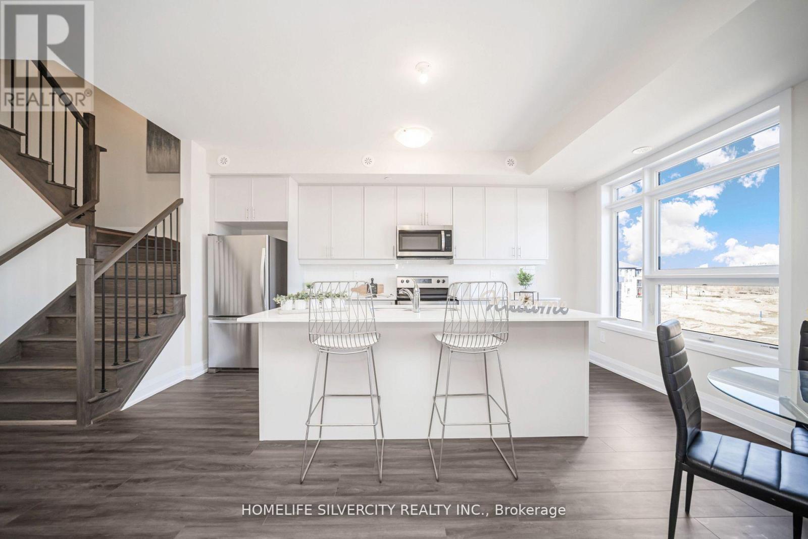 A modern kitchen with white cabinets and a bar area.