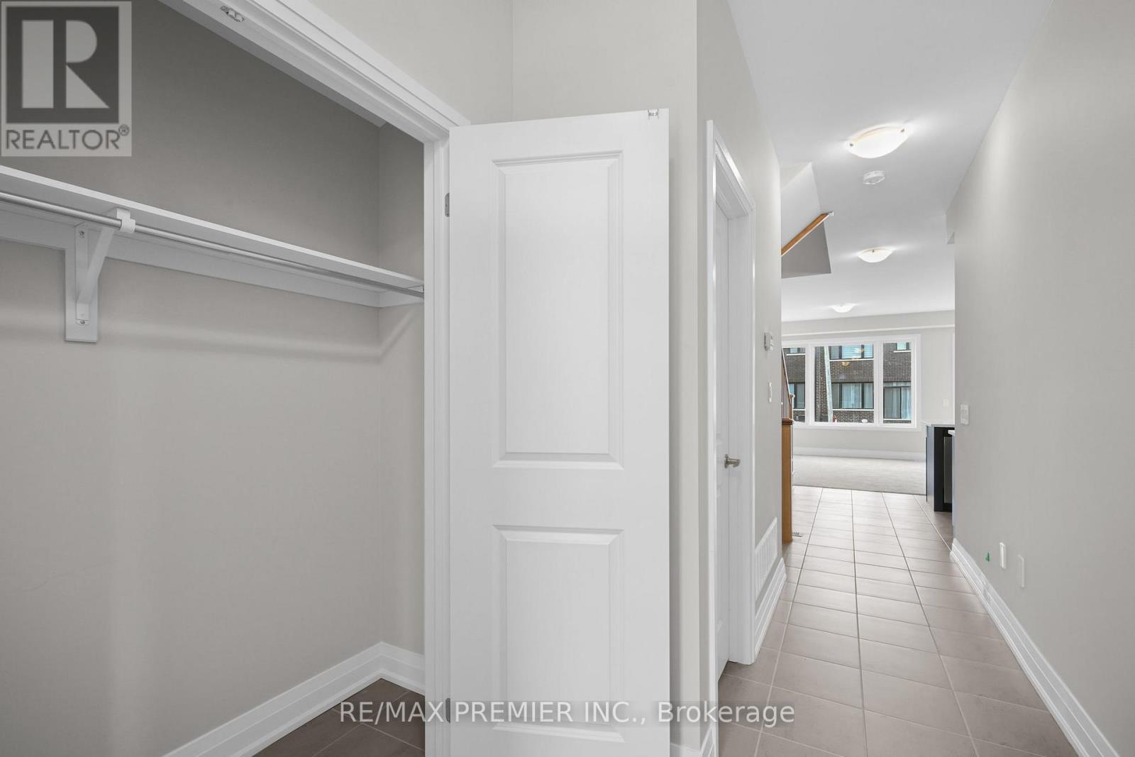 A hallway with a white door and a brokerage sign on the wall.