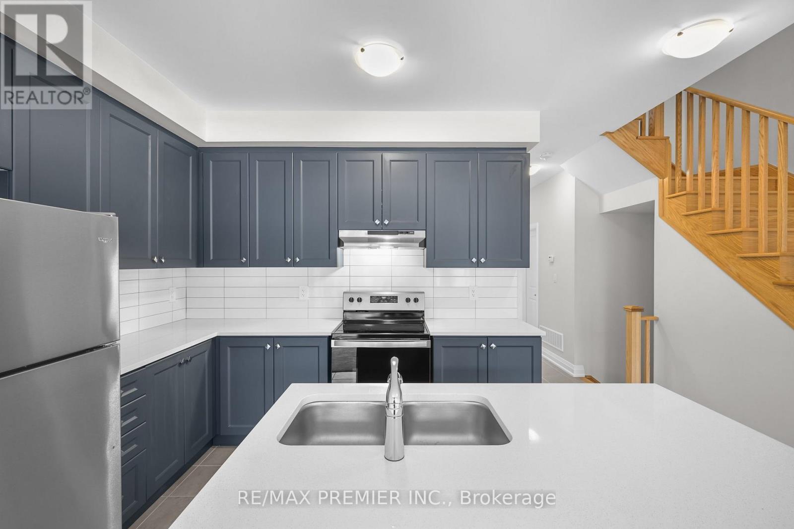 A kitchen with dark blue cabinets and a stainless steel refrigerator.