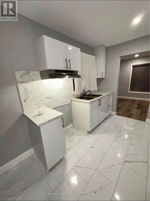 A kitchen with white cabinets and marble countertops.