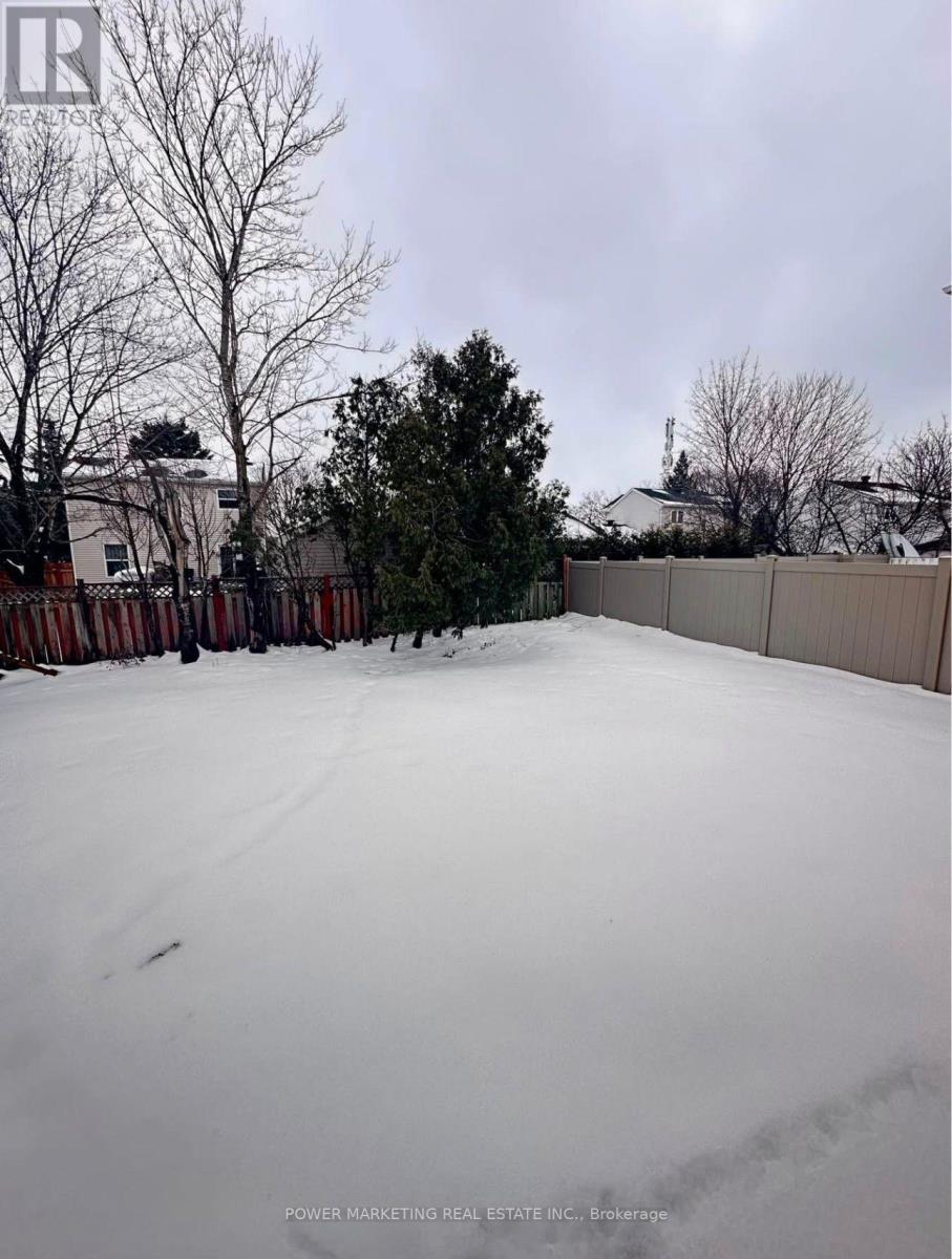 A snow-covered yard with a fence and trees in the background.