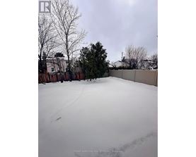 A snow-covered yard with a fence and trees in the background.