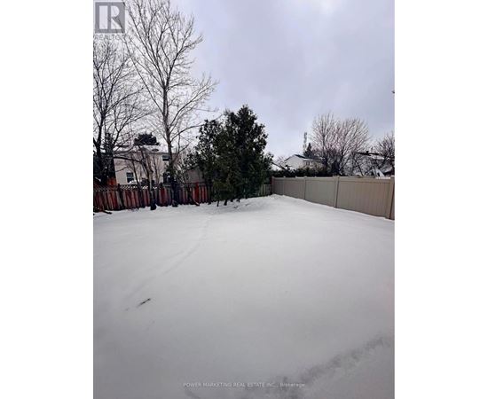 A snow-covered yard with a fence and trees in the background.