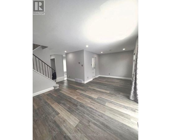 A room with wooden flooring and a staircase.