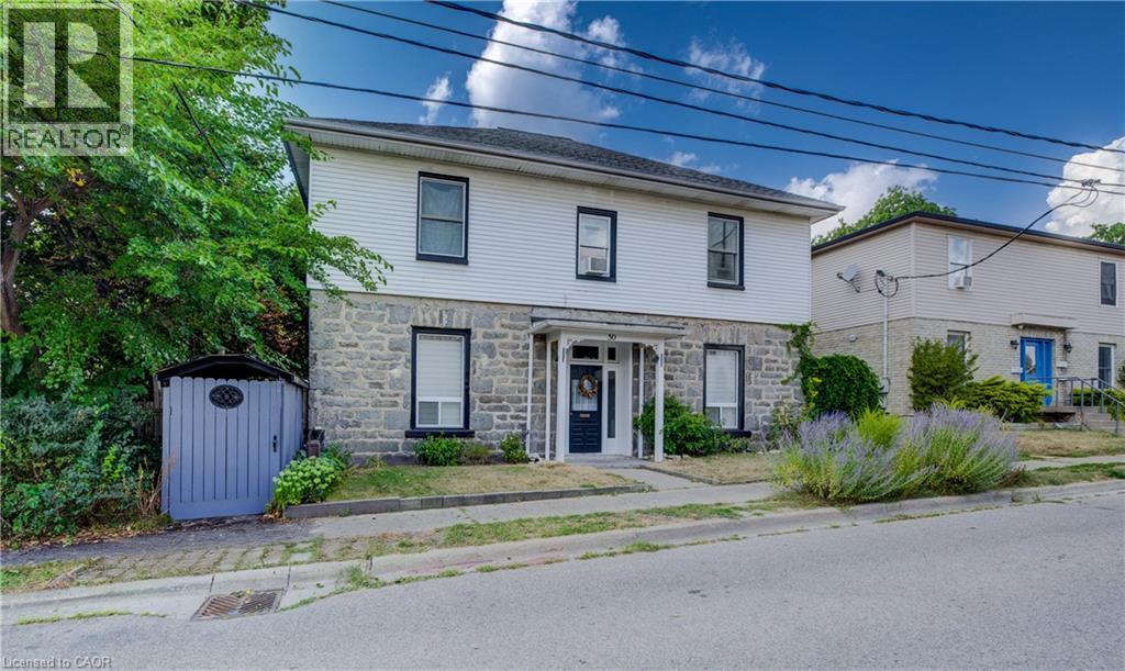 A house with a stone facade and a grey garage door is for sale.