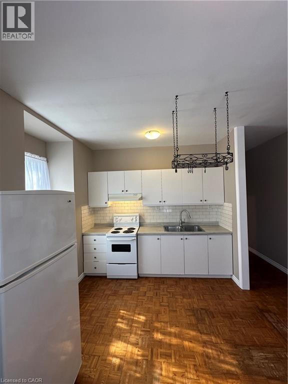 A kitchen with white appliances and wooden floors.