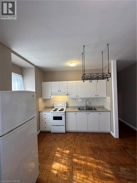 A kitchen with white appliances and wooden floors.