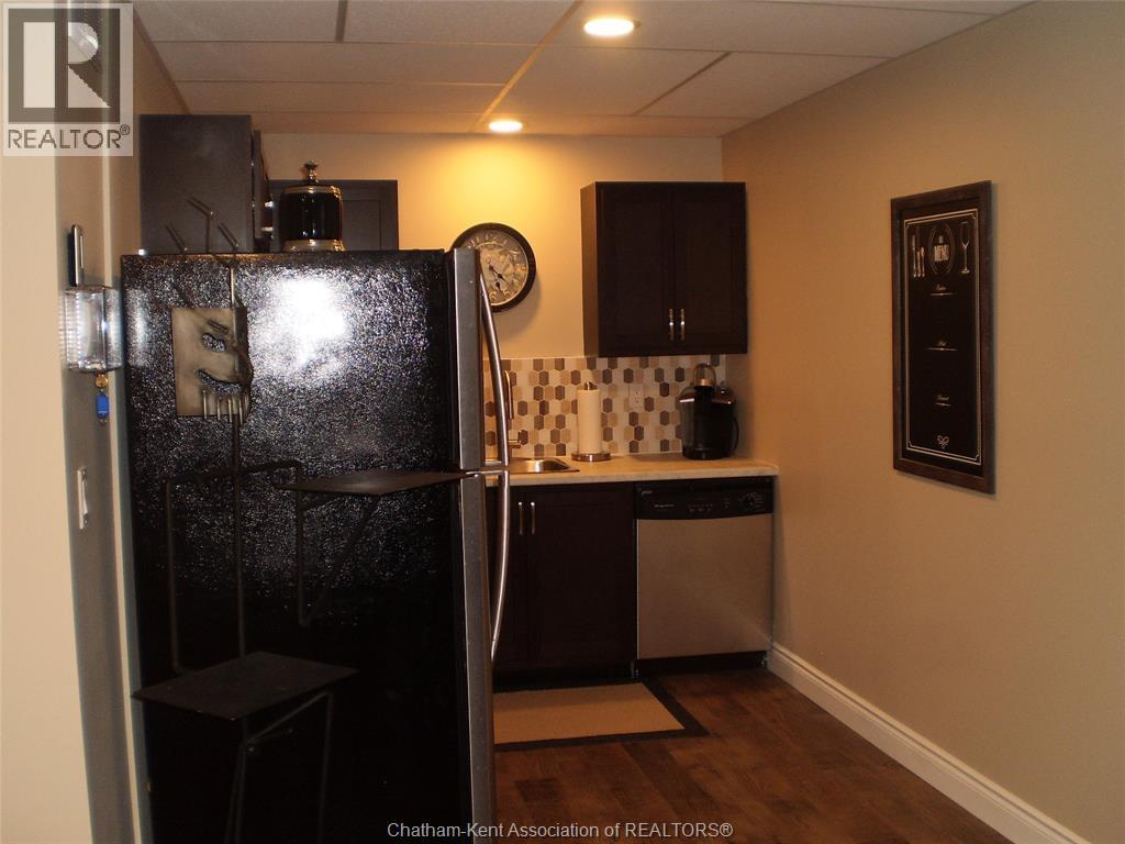 A kitchen with a black fridge and a black stool.