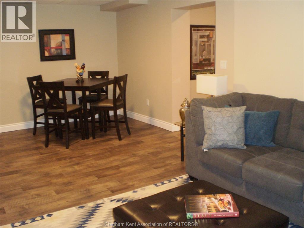 A living room with a grey couch, a wooden dining table with chairs, and a rug on the floor.