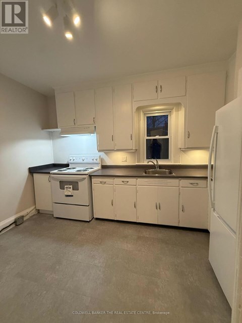 A white kitchen with a sink and a window.