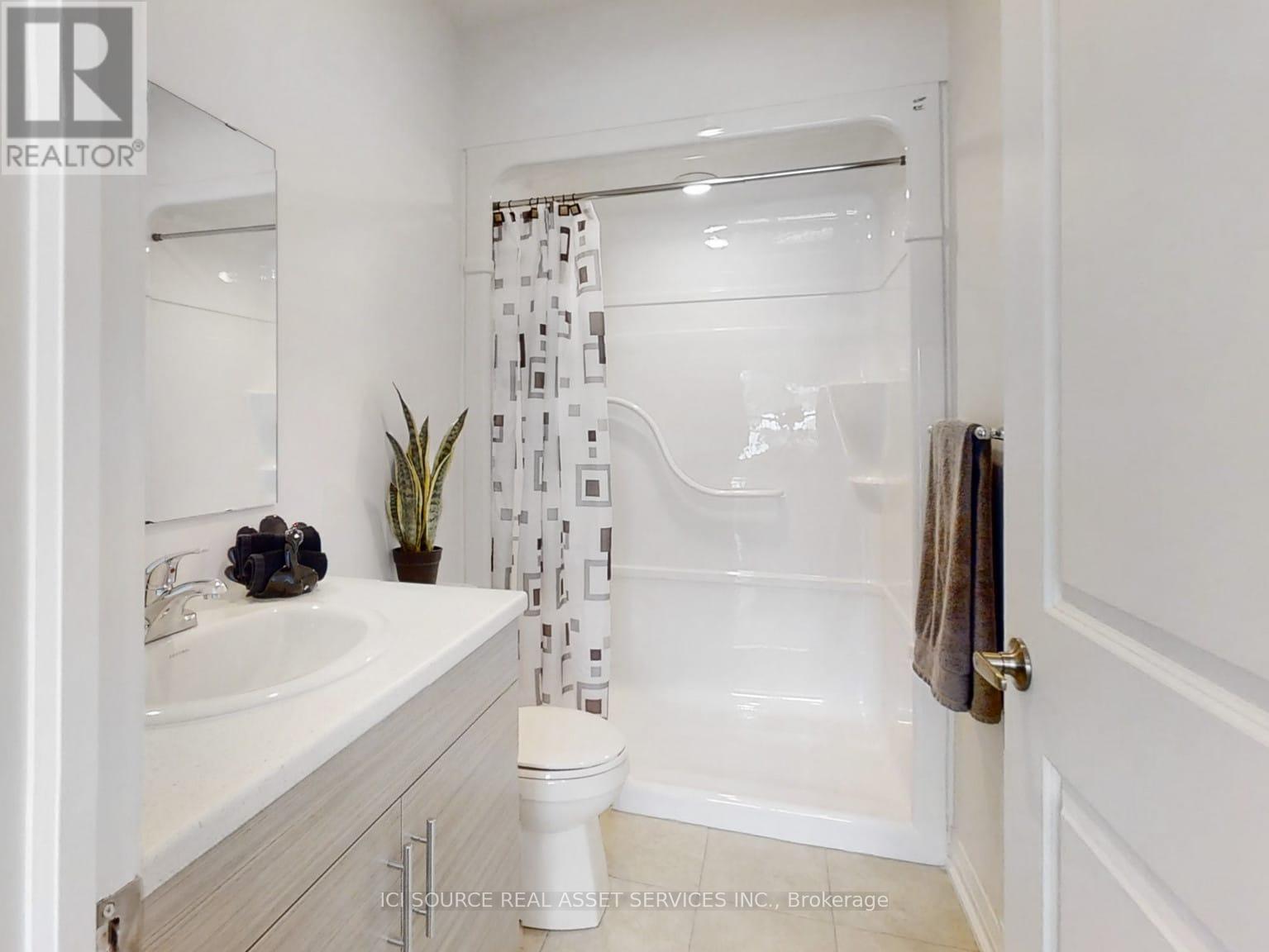 A white bathroom with a toilet, sink, and shower.