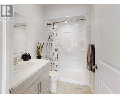 A white bathroom with a toilet, sink, and shower.