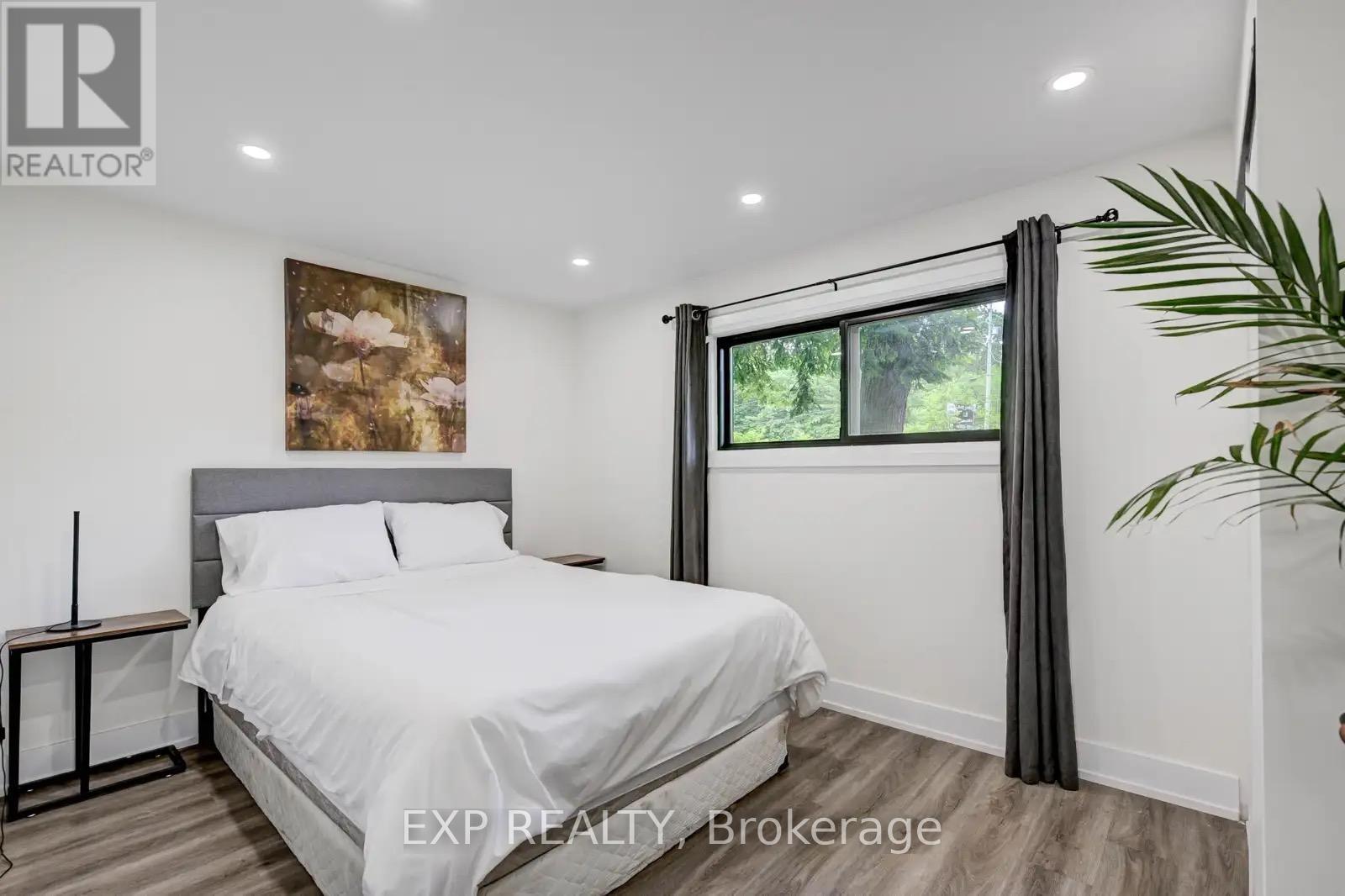 A bedroom with a large bed and a painting on the wall.