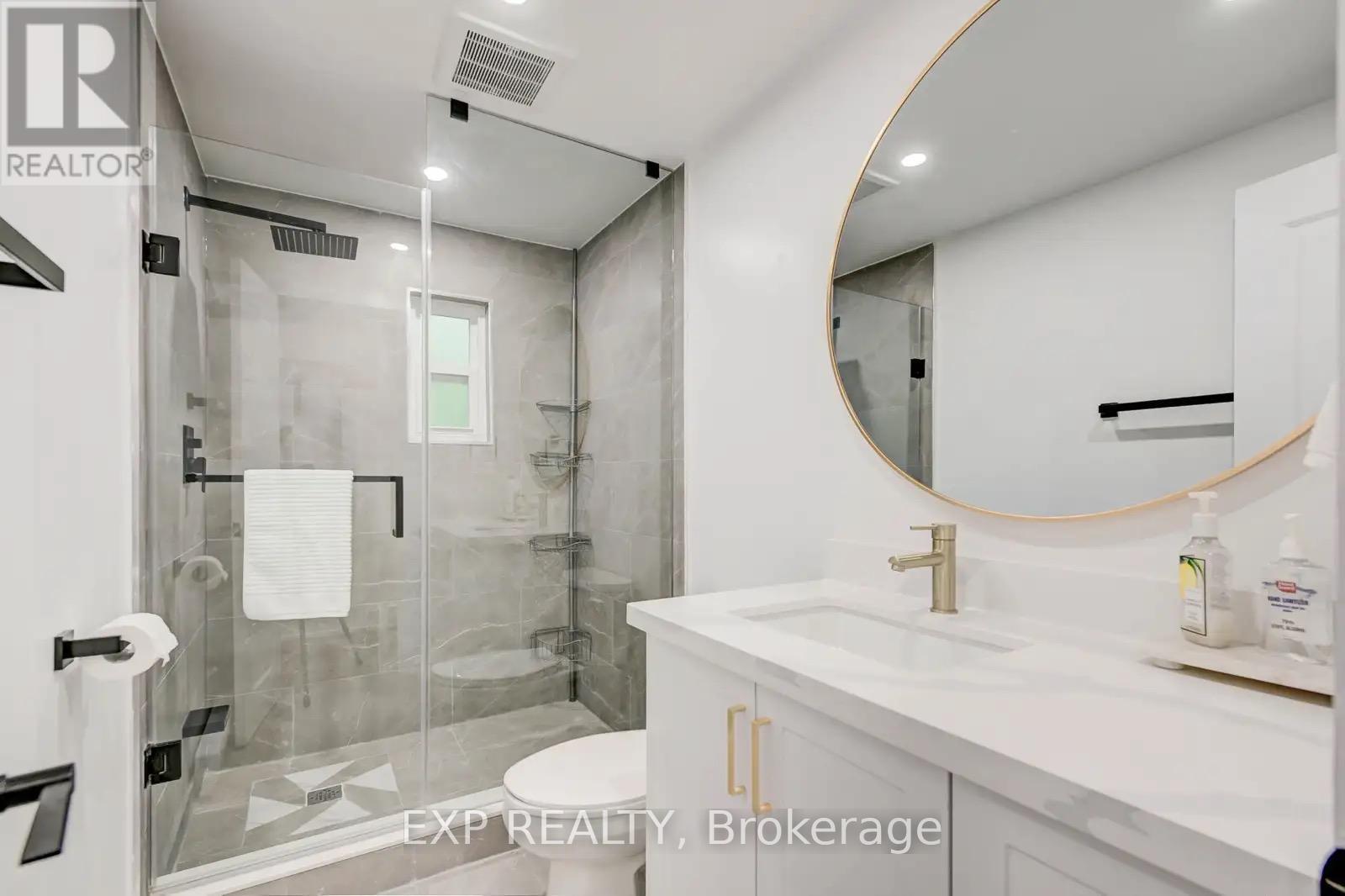A bathroom with a white sink and a round mirror.