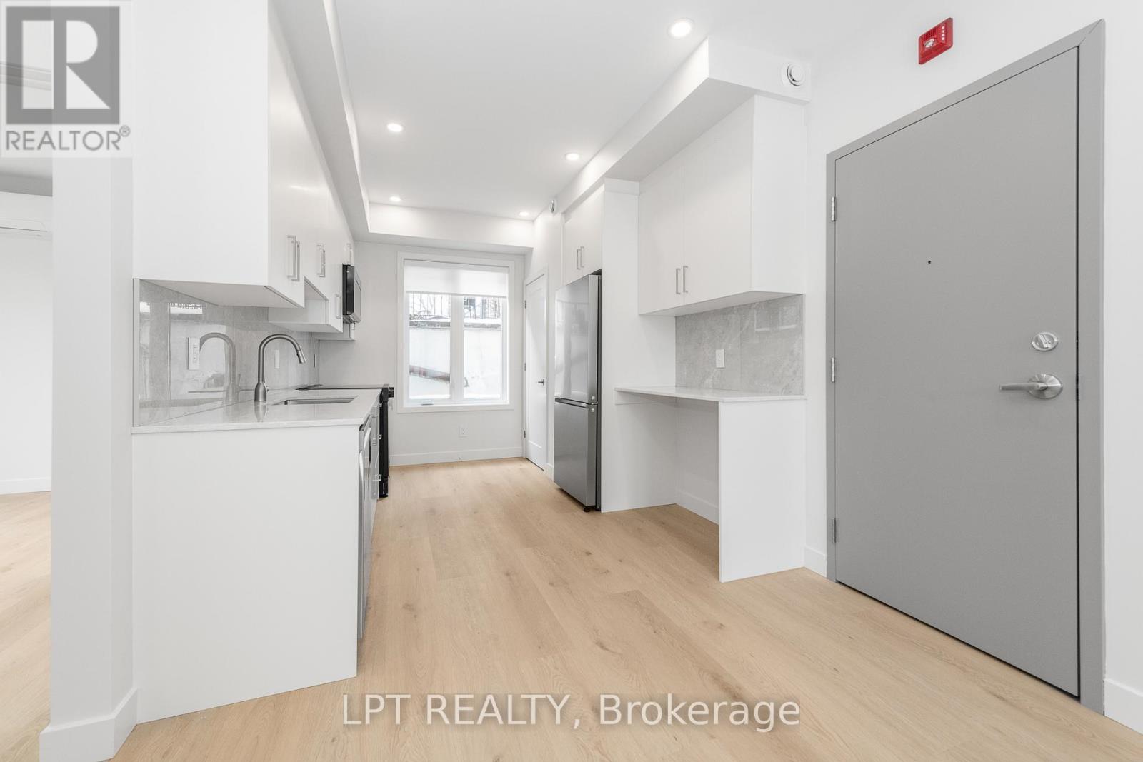 A modern kitchen with white cabinets and a wooden floor.