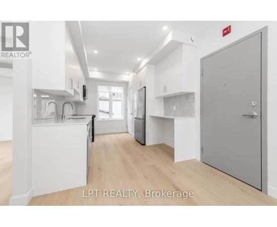 A modern kitchen with white cabinets and a wooden floor.