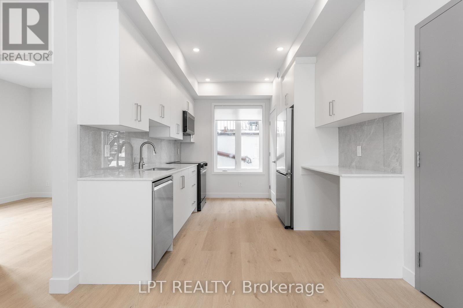 A modern kitchen with white cabinets and stainless steel appliances.