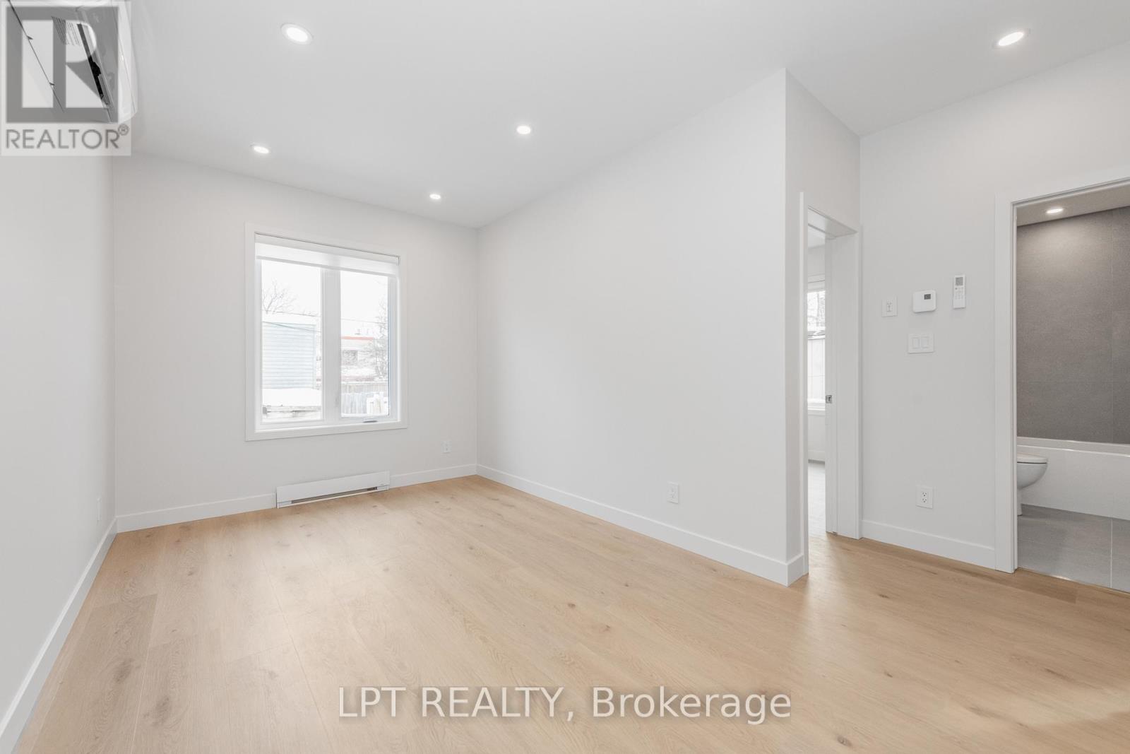 A spacious room with wooden flooring and white walls.