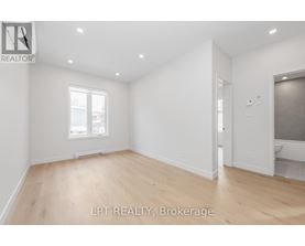 A spacious room with wooden flooring and white walls.