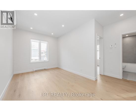 A spacious room with wooden flooring and white walls.