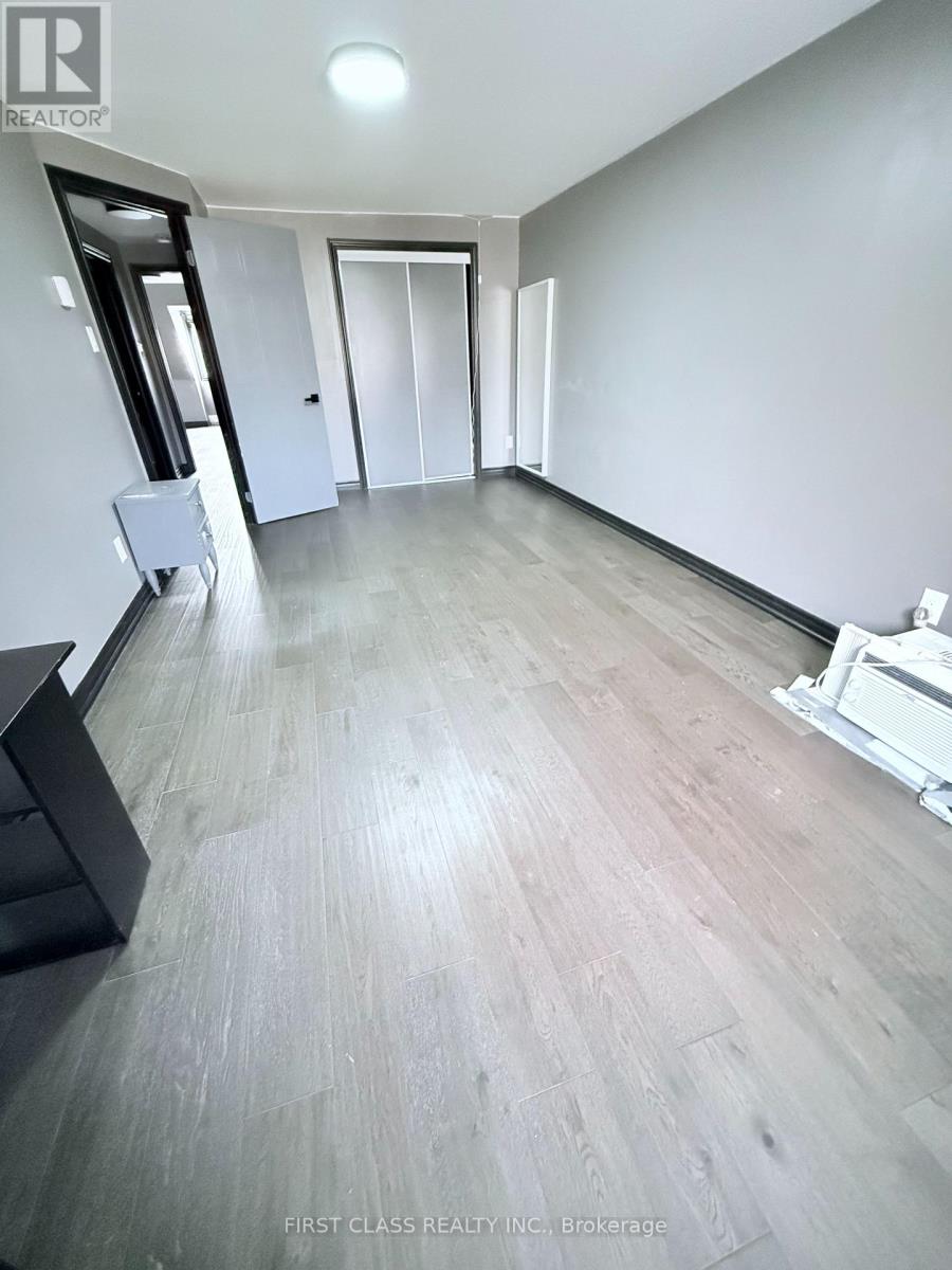 A spacious room with wooden flooring and white walls.