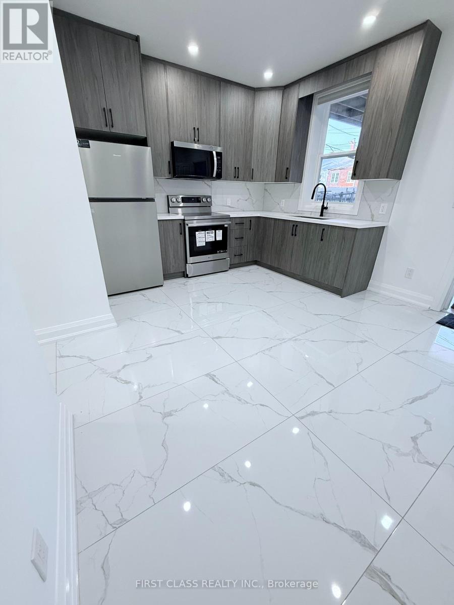 A kitchen with marble flooring and grey cabinets.