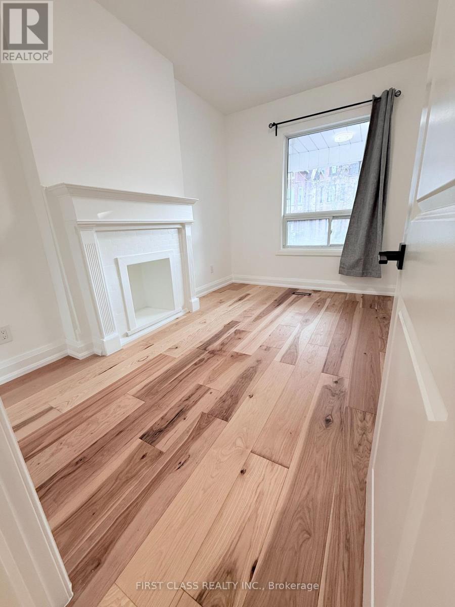 A room with wooden flooring and a window with a grey curtain.