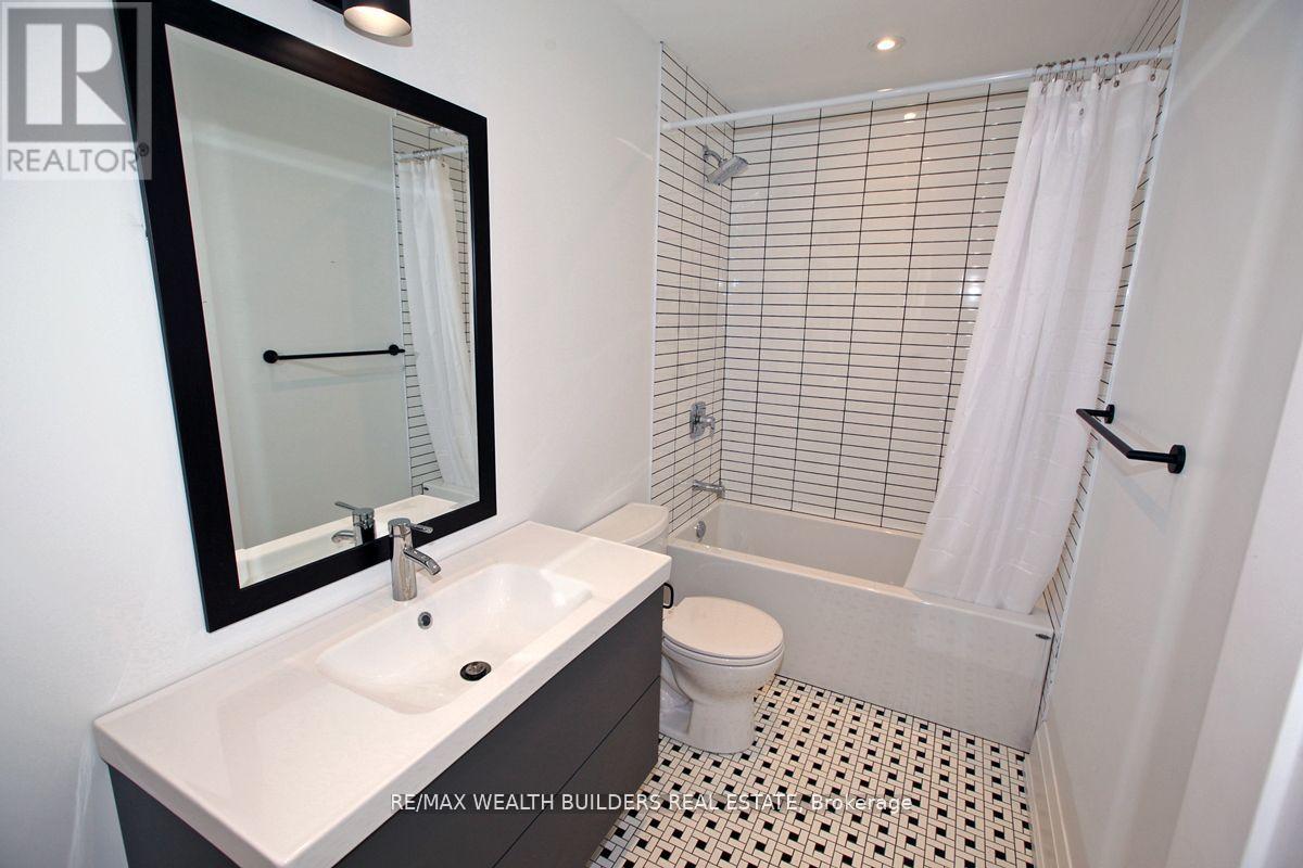 A bathroom with a white sink and a black mirror.