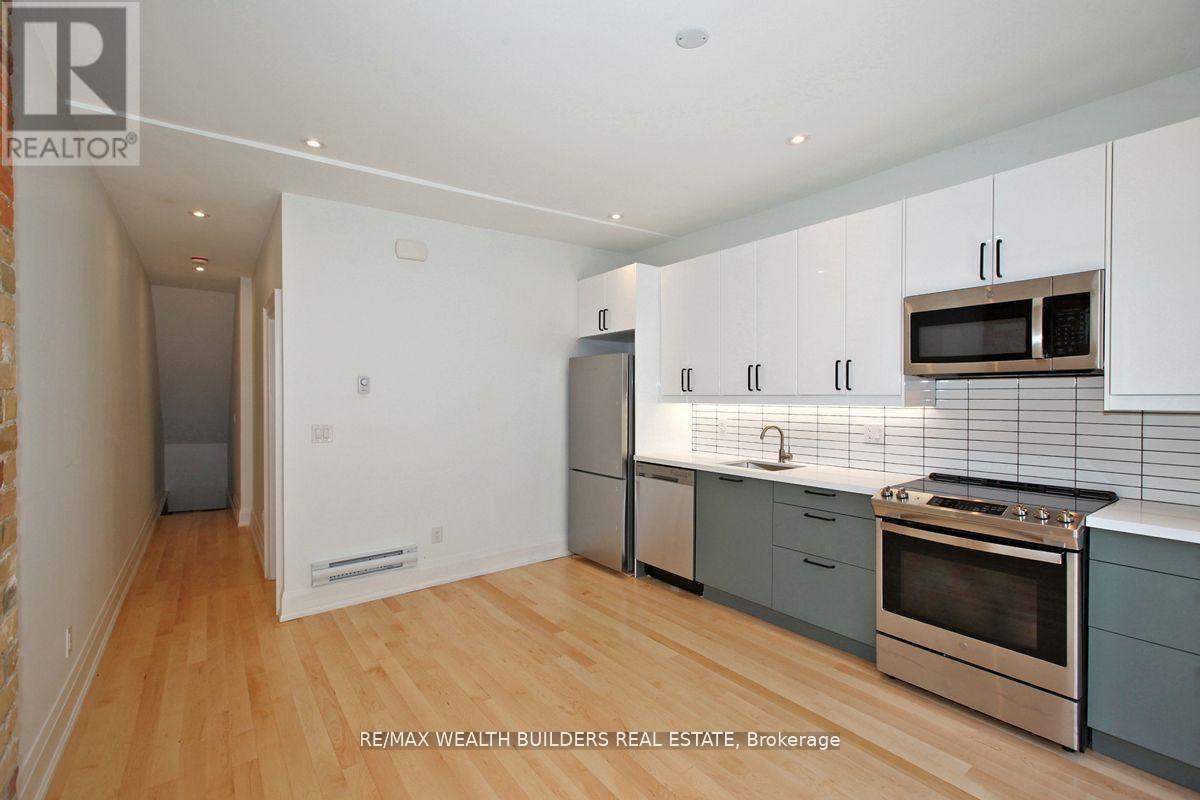 A kitchen with white cabinets and a wooden floor.