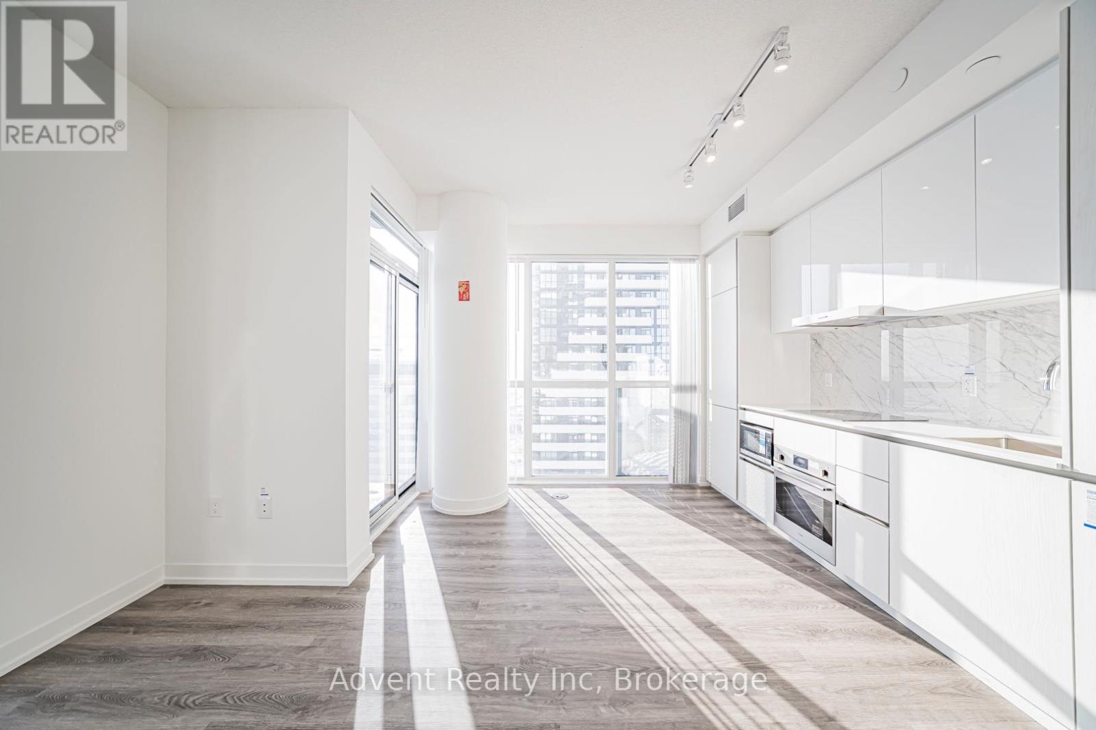 A spacious kitchen and living room with white cabinetry and a view of the city.