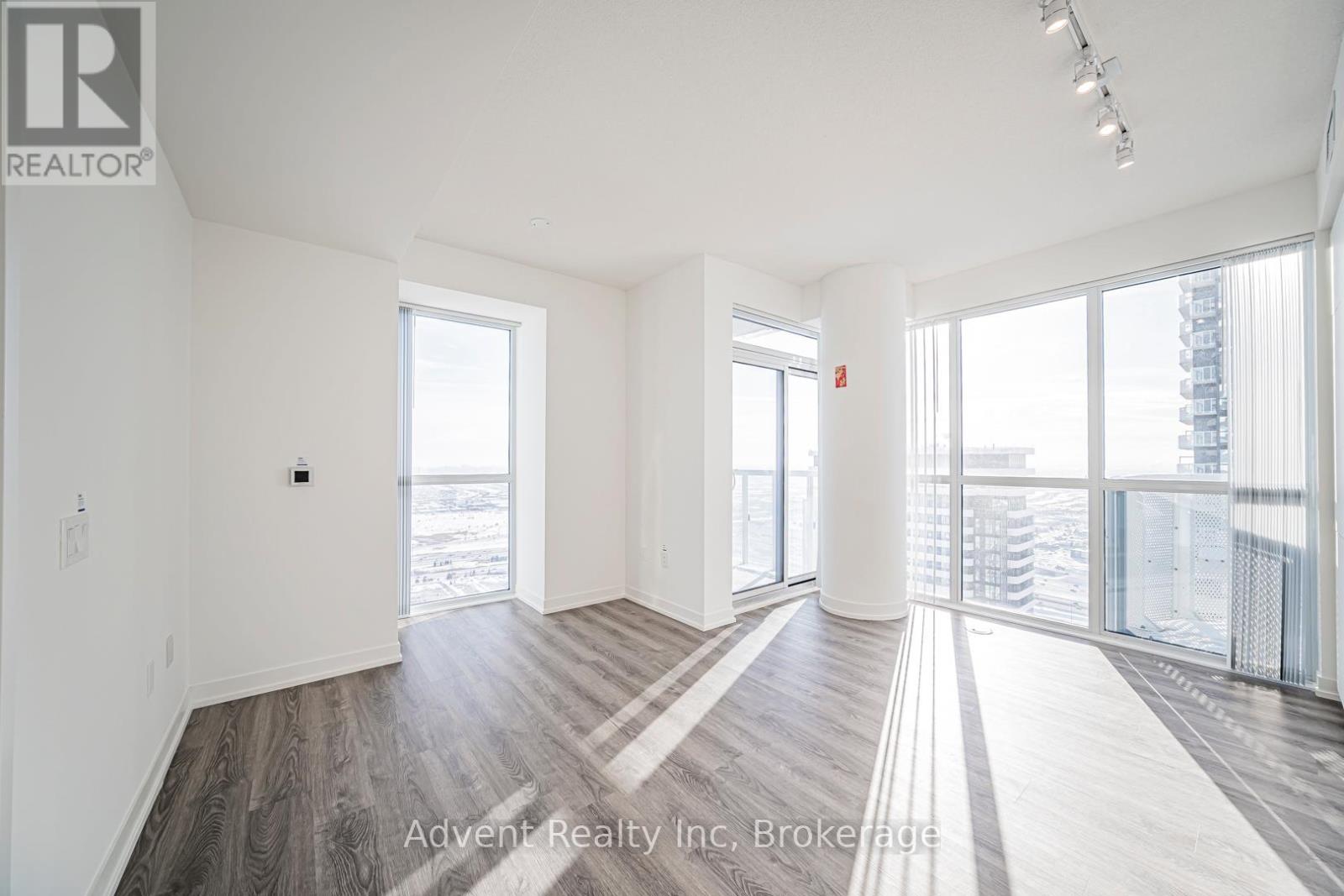 A spacious room with wood flooring and large windows.