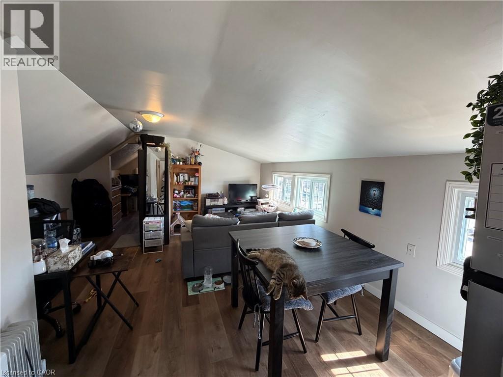 A living room with a dining table and chairs, a couch, and a television.