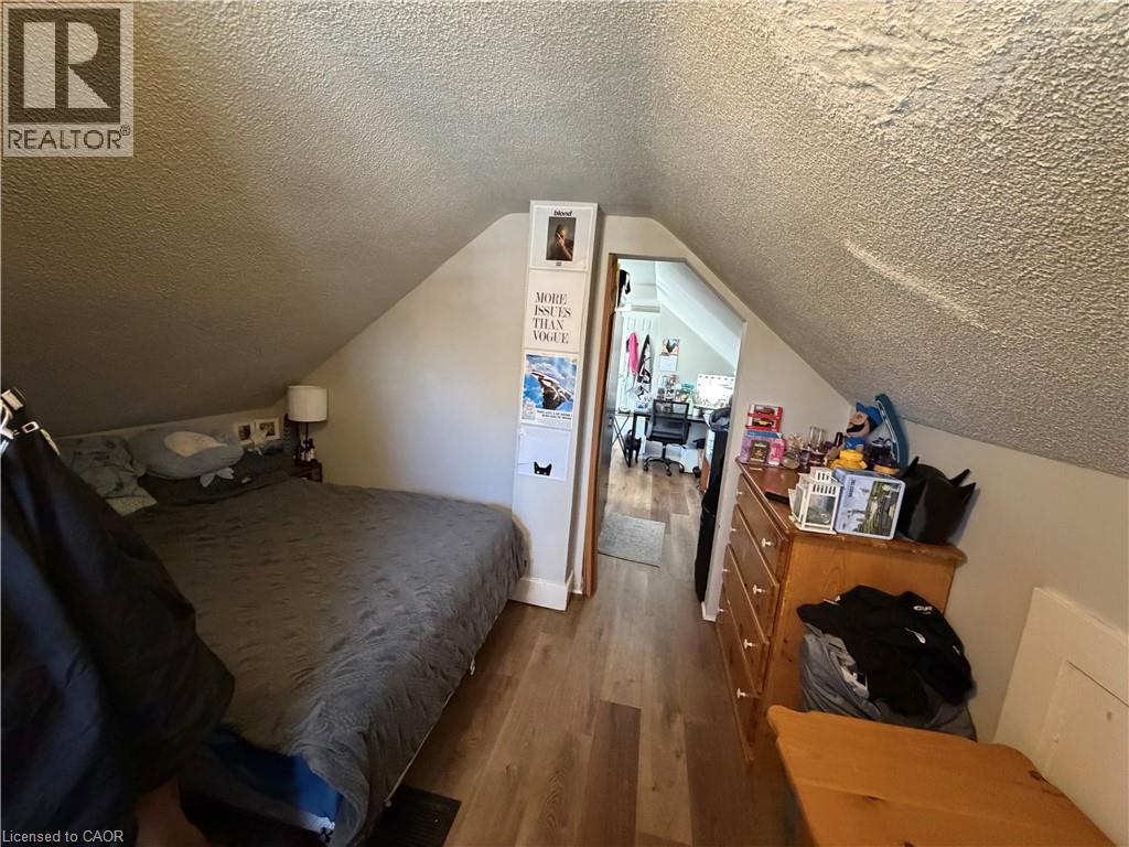 A bedroom with a bed, dresser and a poster on the wall.