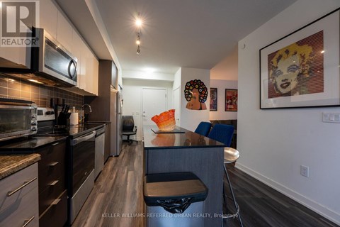 A kitchen with a black counter top and a fridge.