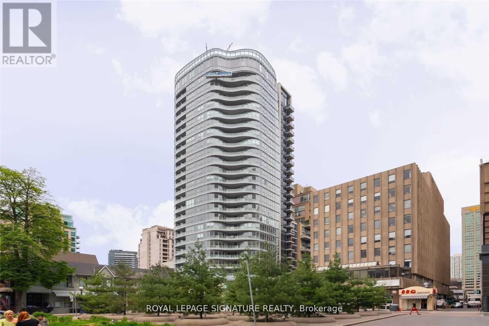 A tall building with a curved design stands in front of other buildings.