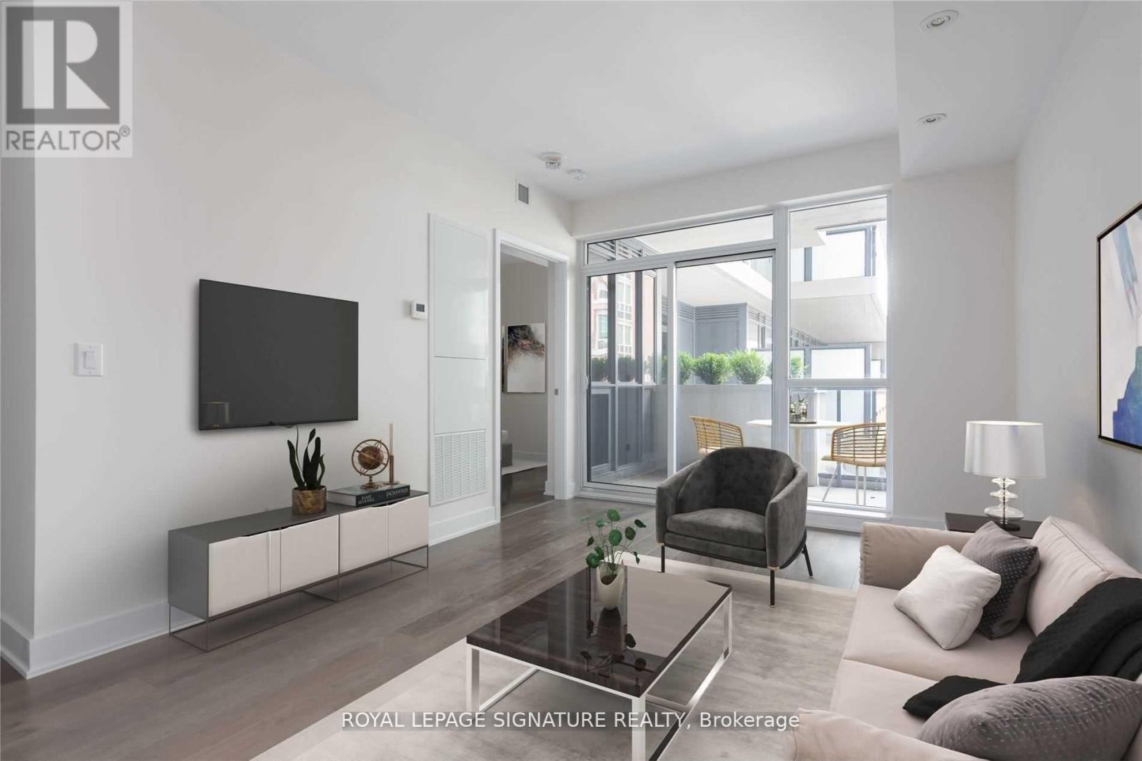 A modern living room with a glass coffee table and a flat screen TV mounted on the wall.