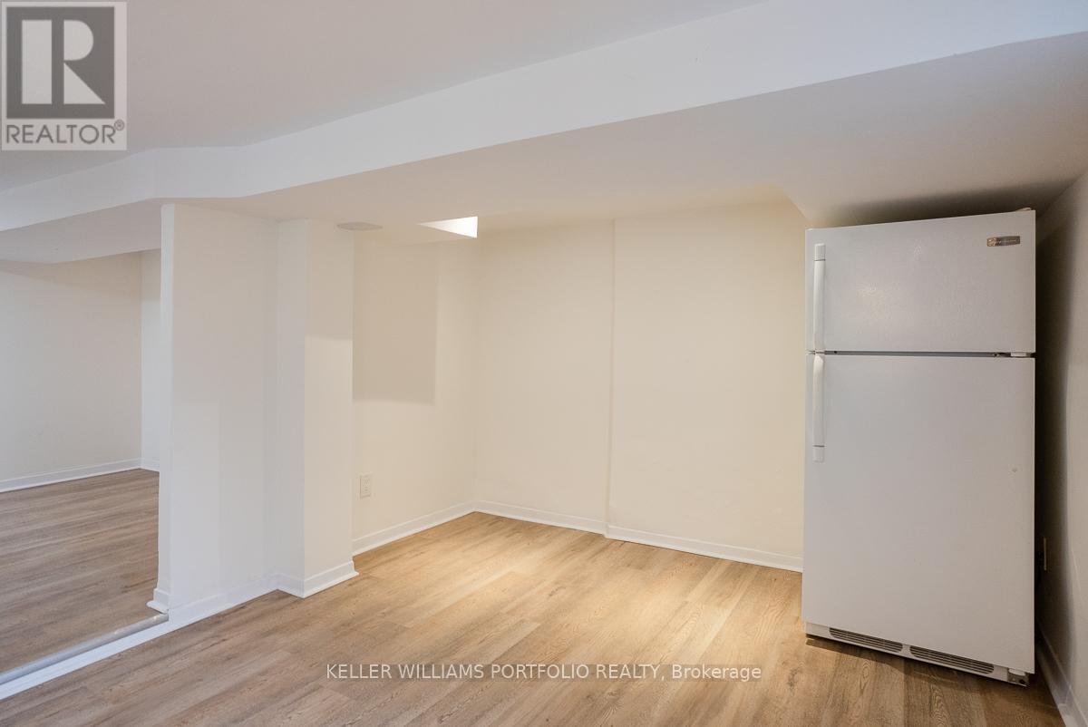A white refrigerator is in a room with wood flooring and white walls.