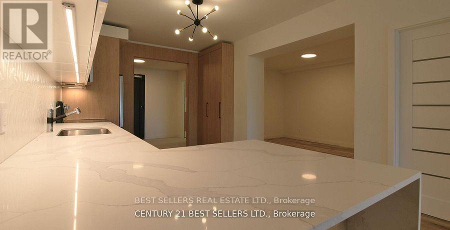 A modern kitchen with a marble countertop and wooden cabinets.