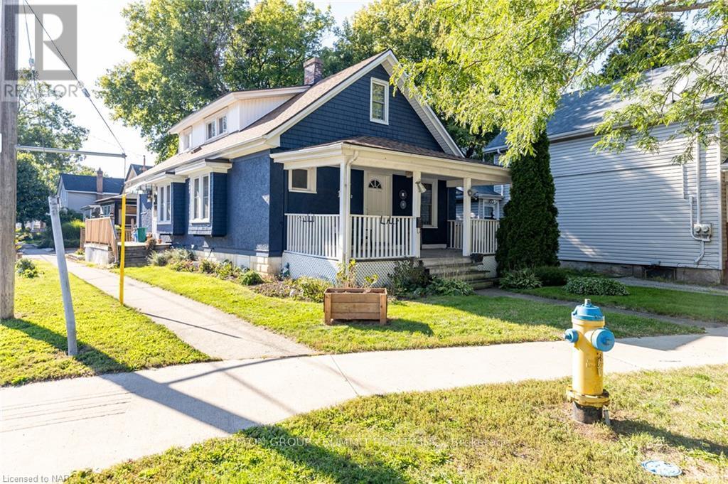 A blue house with a white porch and a yellow fire hydrant in front.